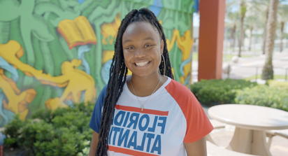 Student standing smiling against a graffiti wall art