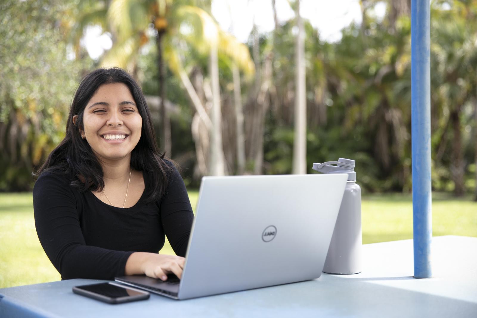 FAU Student smiling with a laptop